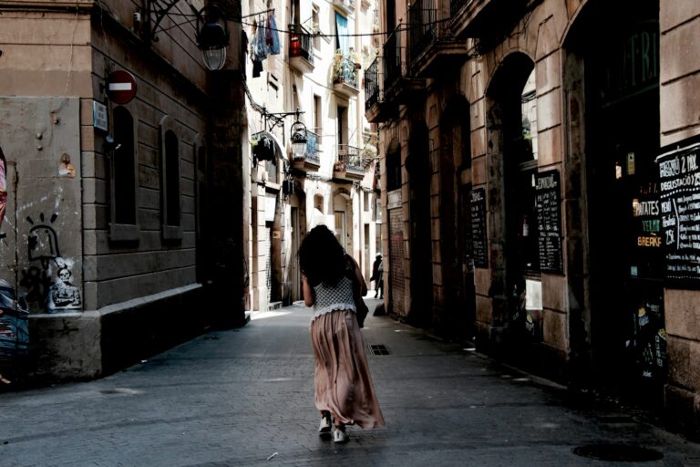 woman in red dress walking on sidewalk during daytime in Barcelona